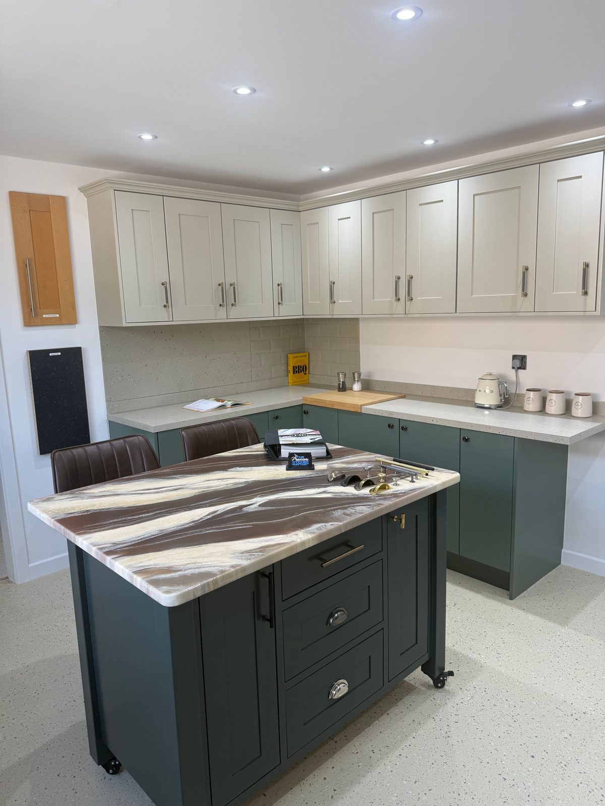 The Premiere Kitchen Painting Co. showroom display kitchen with a hand-painted green island and cream cabinets